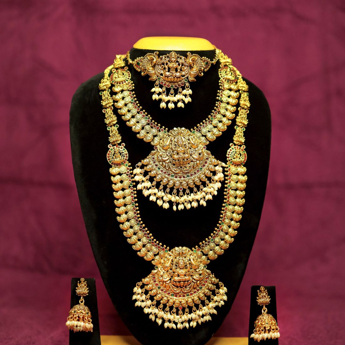 Traditional gold necklace and earring set on a display stand